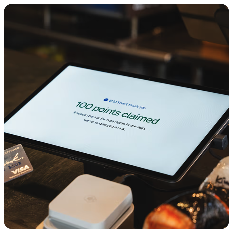 Tablet screen showing a message confirming 100 points claimed and $12.13 paid, with instructions to redeem points for free items via an app.