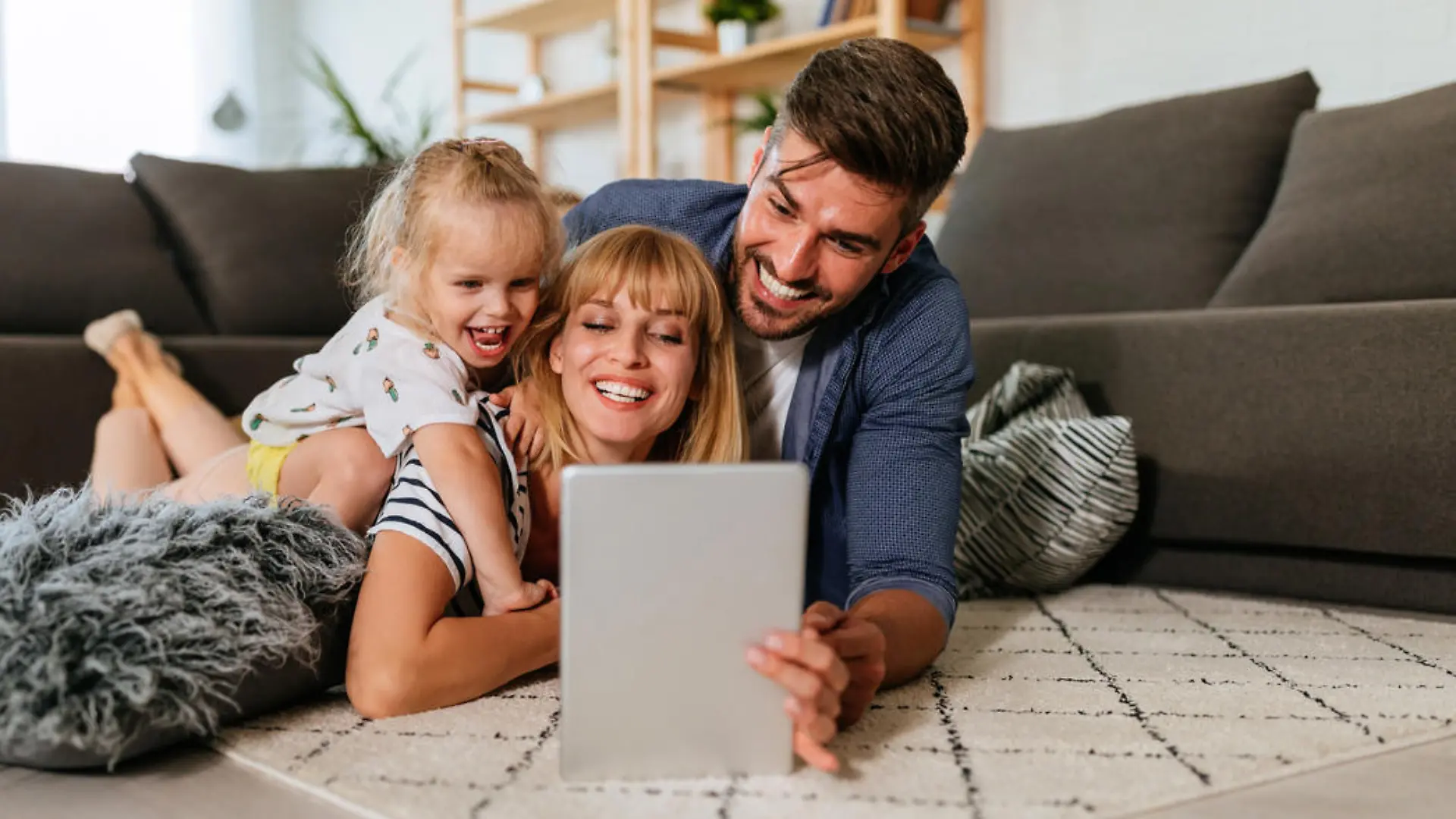 Familie nutzt gemeinsam entspannt ein Tablet auf dem Sofa