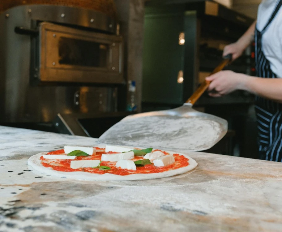 Un pizzaiolo qui enfourne une pizza