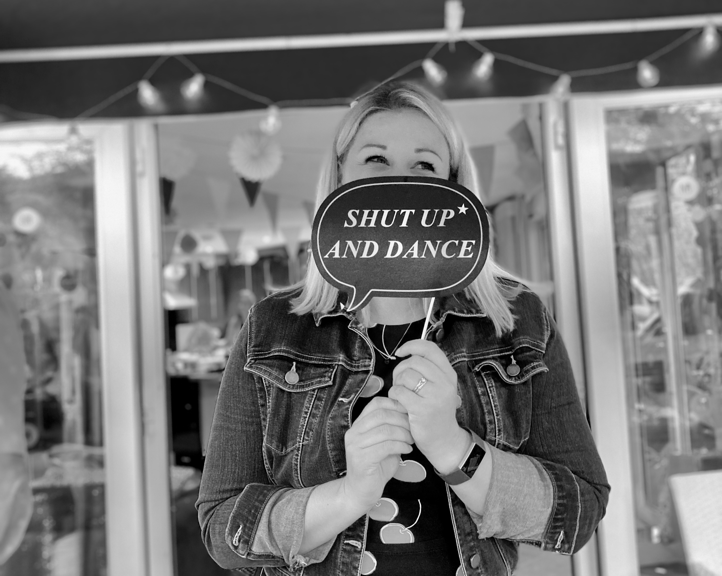 Young girl in a light green dress jumping high on a large inflatable outdoor trampoline under a blue sky.