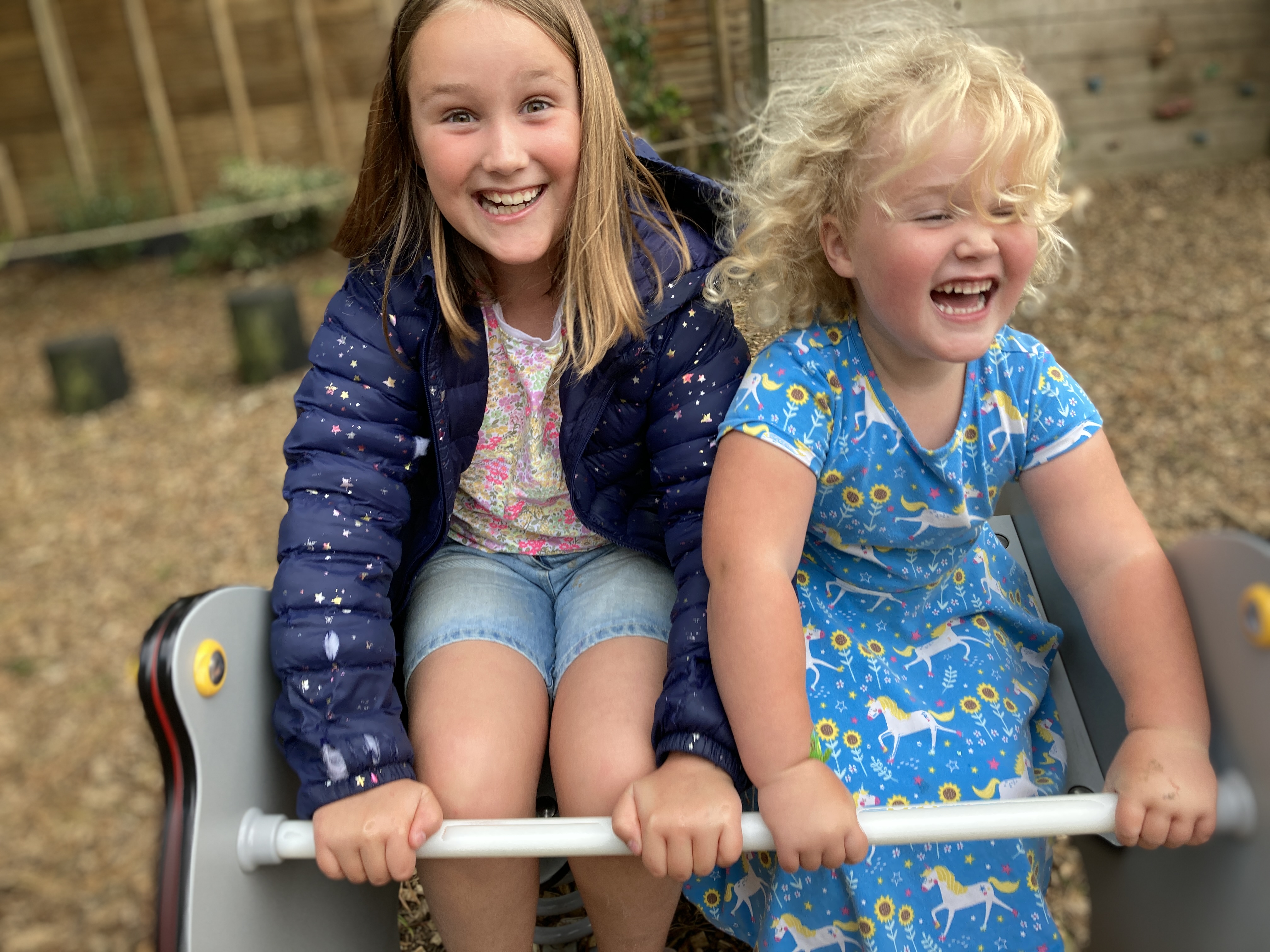 Seven children crouching by a pond surrounded by large green leaves and tropical plants.