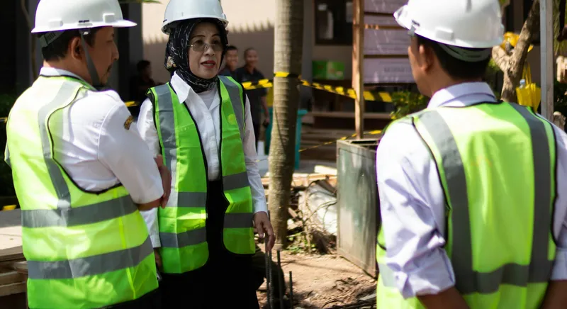 Three workers in hard hats and high-visibility vests talking on site during a safety briefing