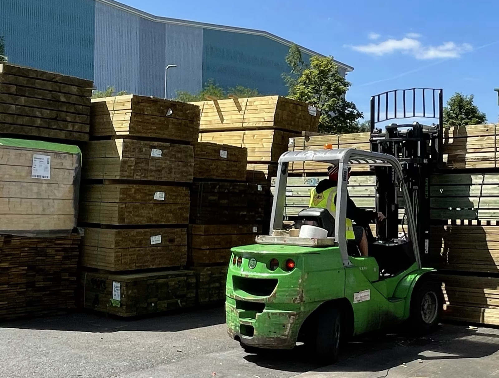 Forklift truck lifting a pack of timber in a builders merchant yard