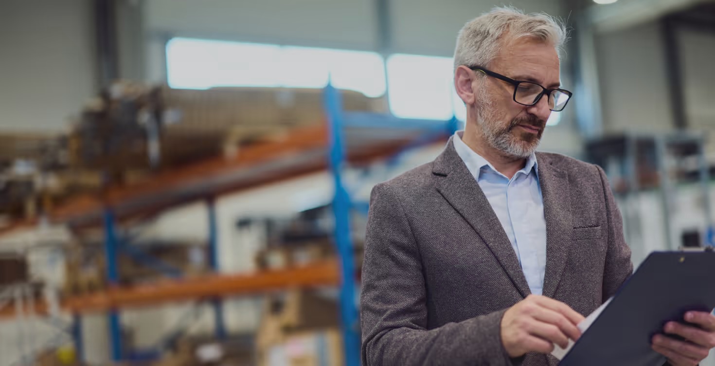 Health and safety consultant reviewing a checklist on a clipboard in a warehouse
