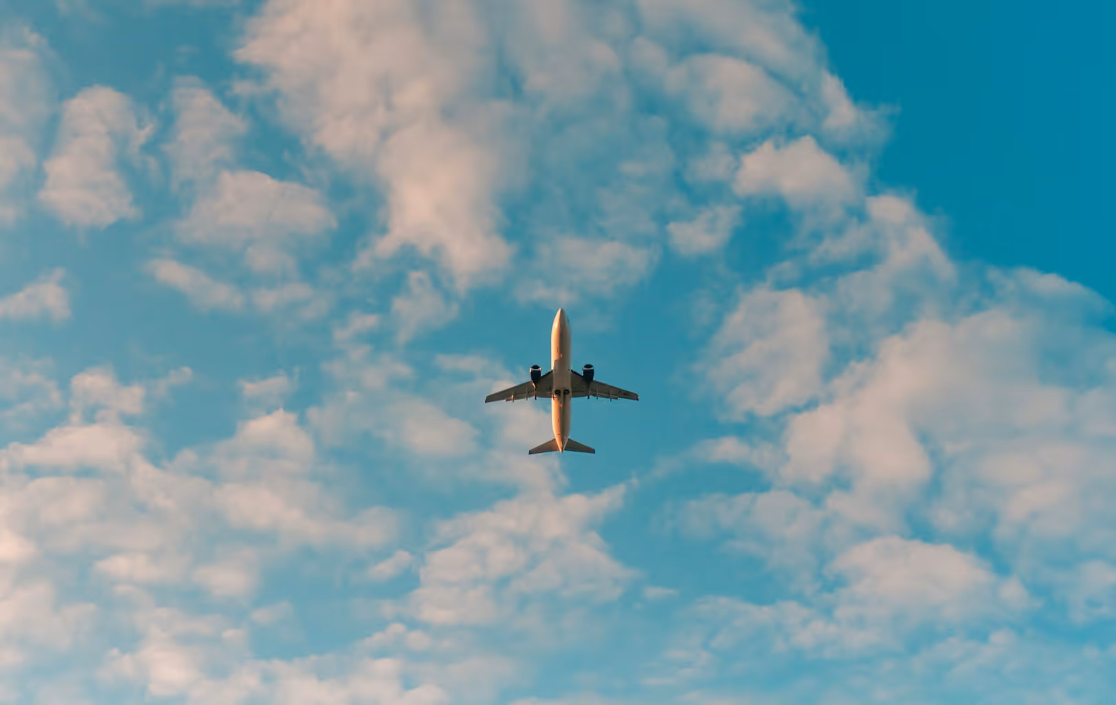 Airplane flying directly overhead through a partly cloudy blue sky.