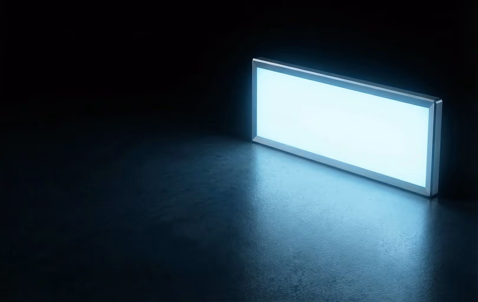 Rectangular LED panel light glowing on a dark textured surface.