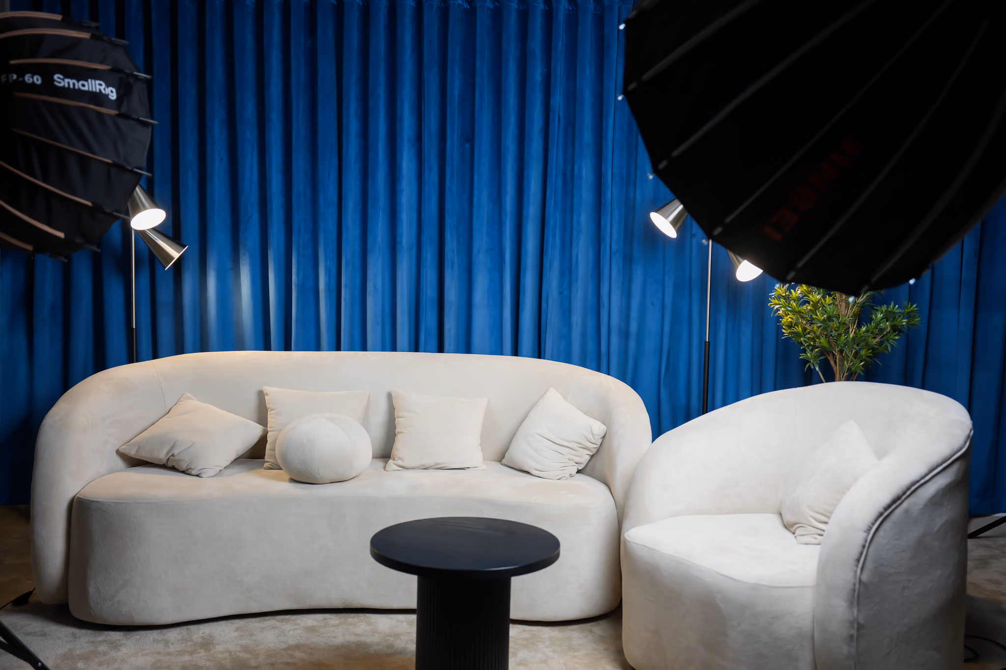 Sofa podcast Setup with blue curtains and plants in the background