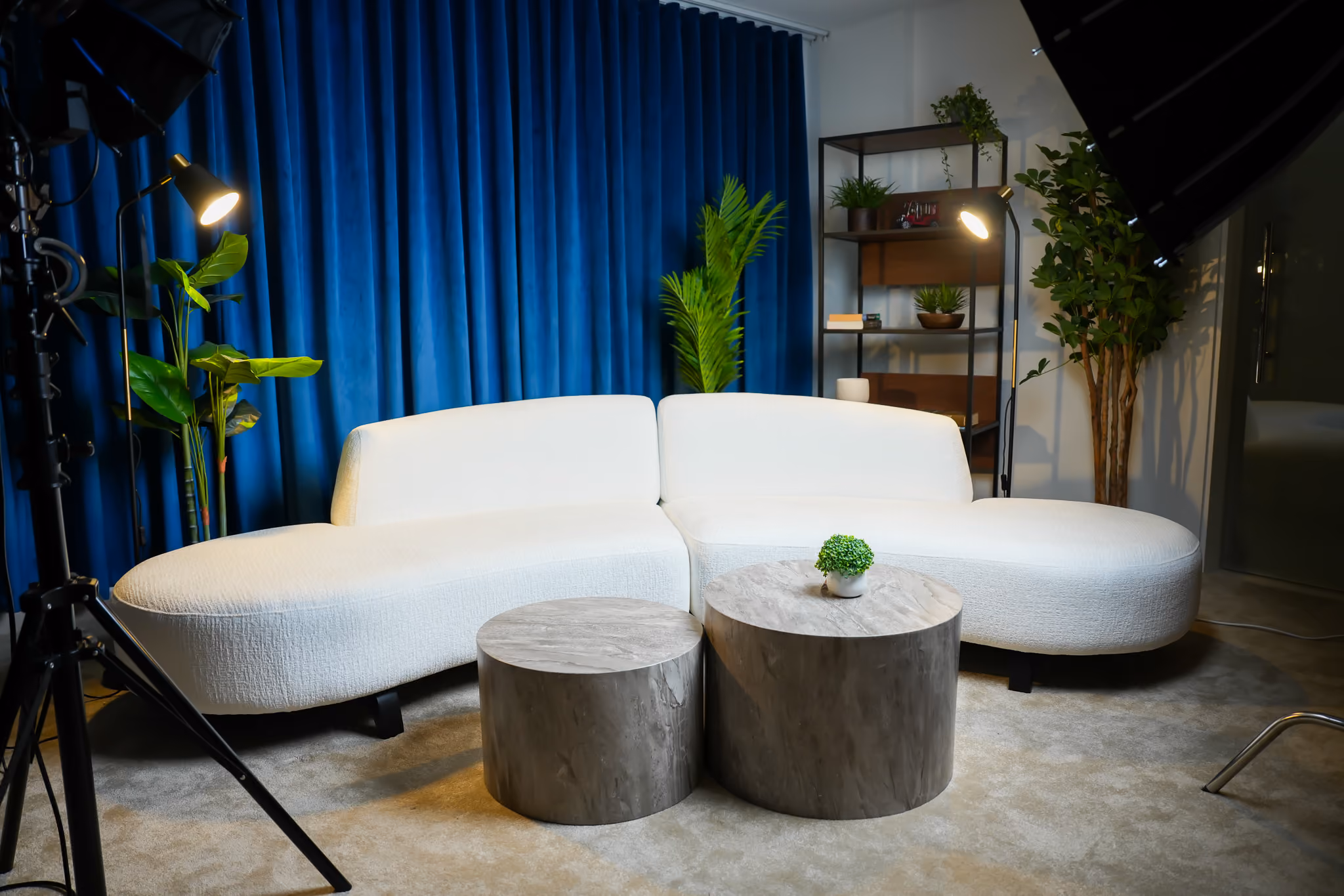 Modern sofa setup with 2 headlights, blue curtains and a shelf in the back with visual props