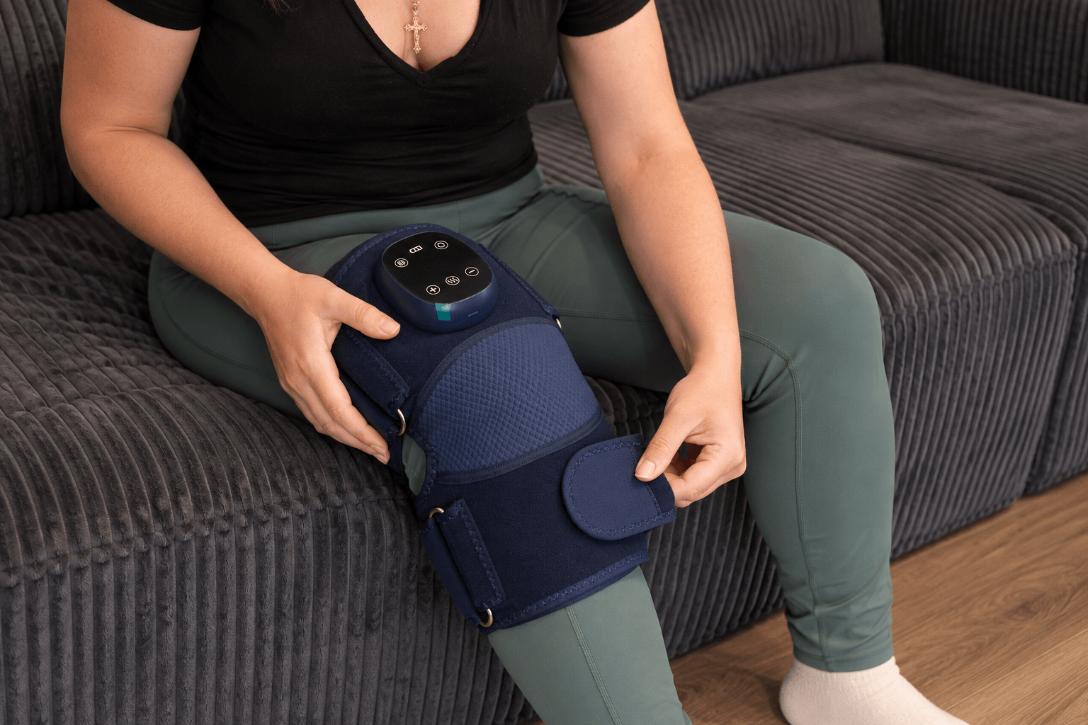 Seated at the couch, securing the Oasis wrap straps around the knee