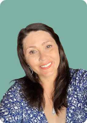 Smiling woman with long dark hair wearing a blue and white patterned top and silver earrings against a light green background.