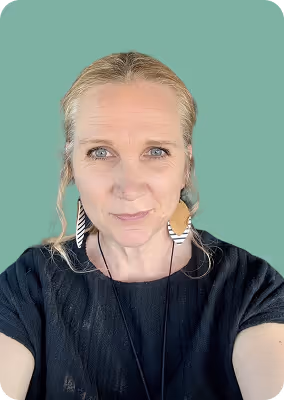 Woman with blonde hair pulled back, wearing black top and unique black and white earrings on teal background.