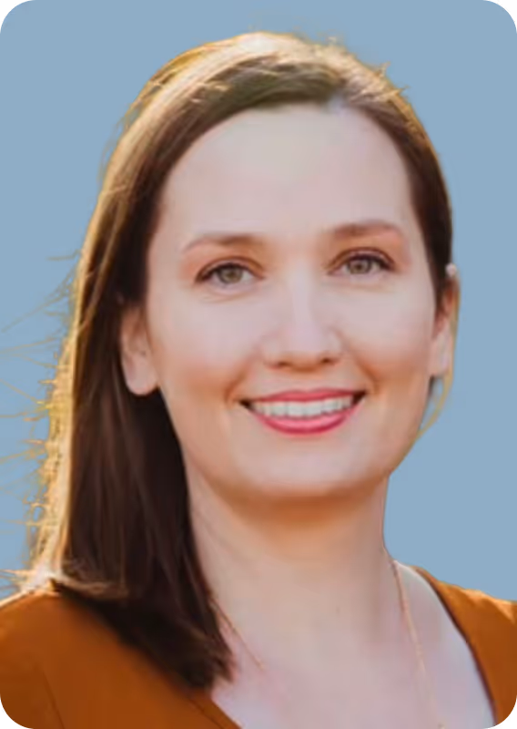 Portrait of a smiling woman with straight brown hair and wearing an orange top.