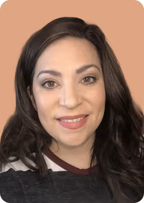 Smiling woman with long dark hair and natural makeup against a plain brown background.
