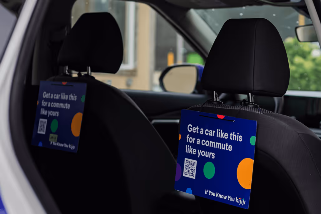 Two car seat headrests with blue signs that say 'Get a car like this for a commute like yours' and a QR code.