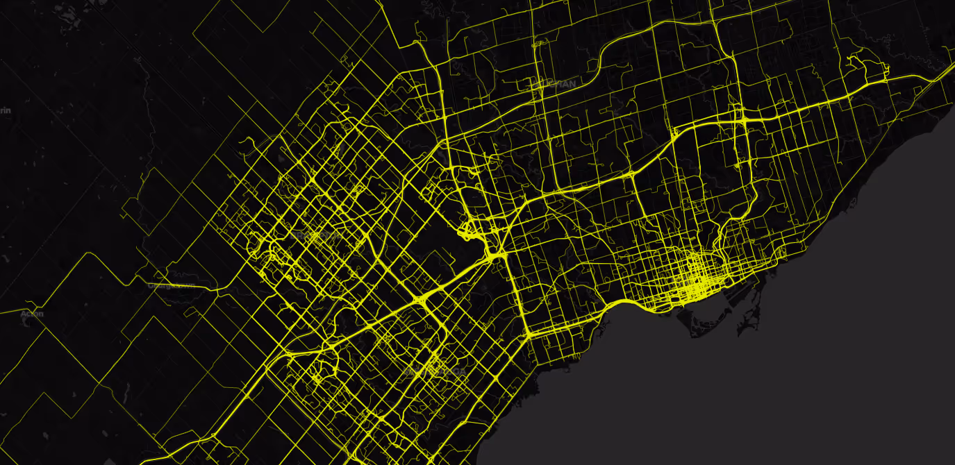 Map showing a city's street network highlighted in bright yellow lines on a dark background, depicting a detailed urban grid near a coastline.