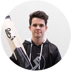 Young man wearing a black hoodie holding a cricket bat, standing against a light background.