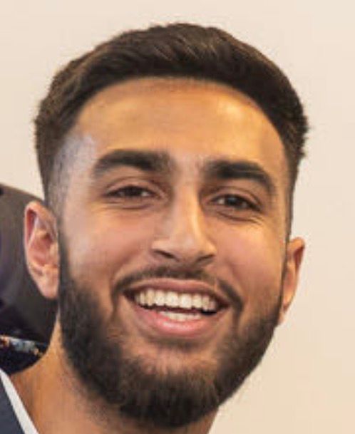 Smiling man with dark hair and beard, looking at the camera.