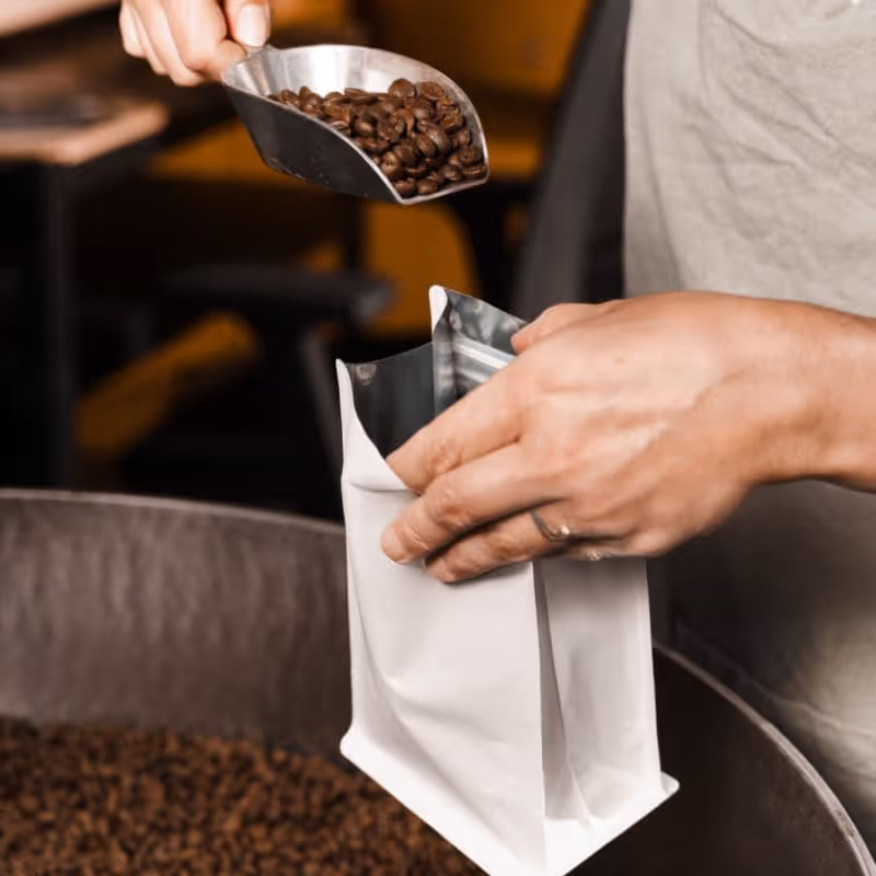 Hands fill packaging with coffee