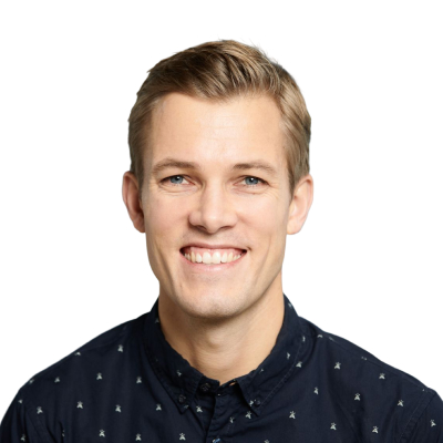 Porträt eines lächelnden Mannes mit kurzem blonden Haar und blauem Hemd vor weißem Hintergrund.