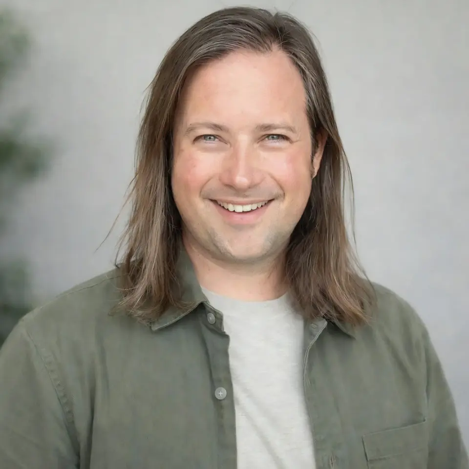 Professional headshot of a man in a green button down over a t-shirt.