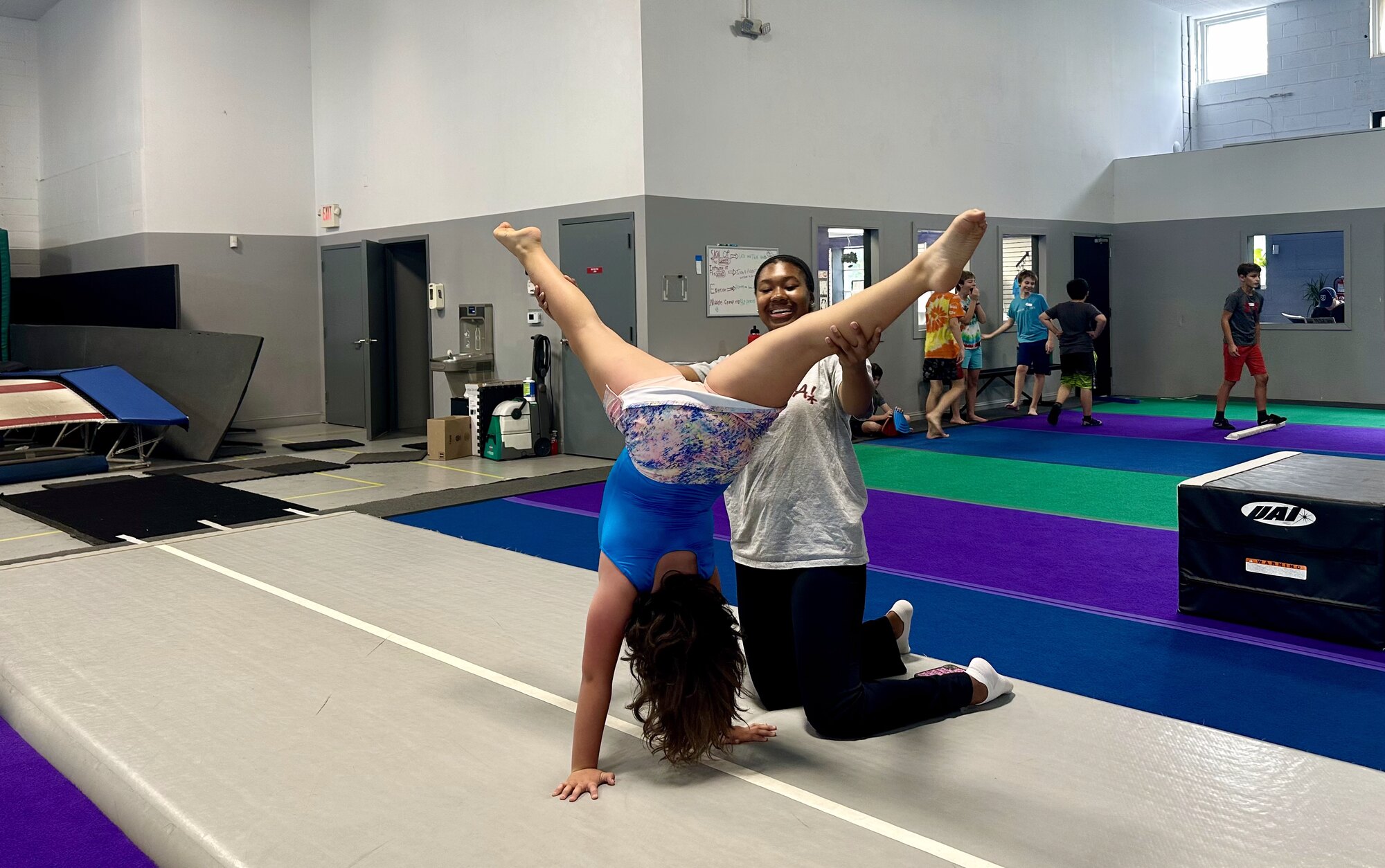 Coach spotting a gymnast in a straddle handstand at Dynamite Gymnastics