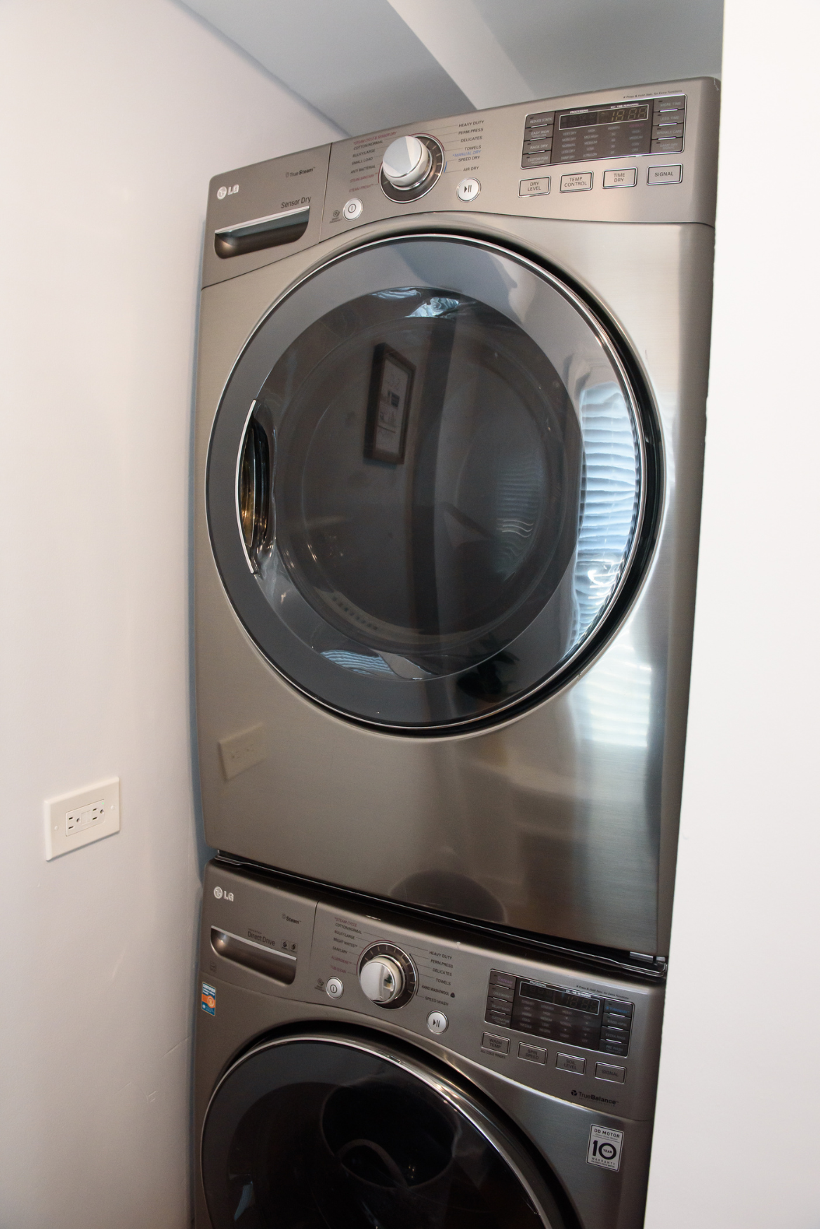 Stacked silver LG front-load washer and dryer unit in a laundry room.