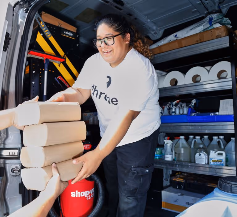 throne technician karla happily handing over paper towels from the throne van to restock a throne unit