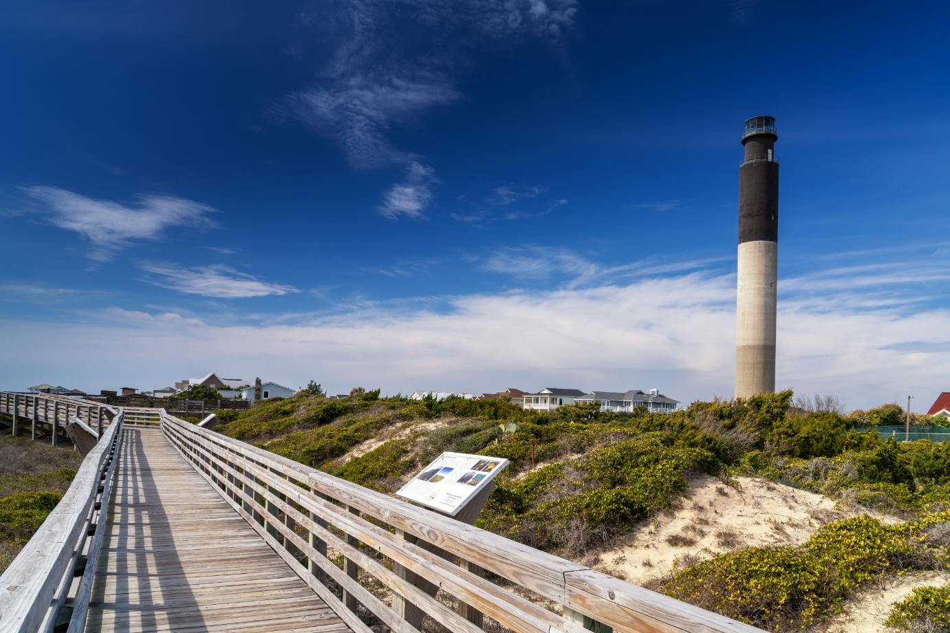 view of the baordwalk and public beach access at Caswell Beach with thev Oak Island Lighthouse behind