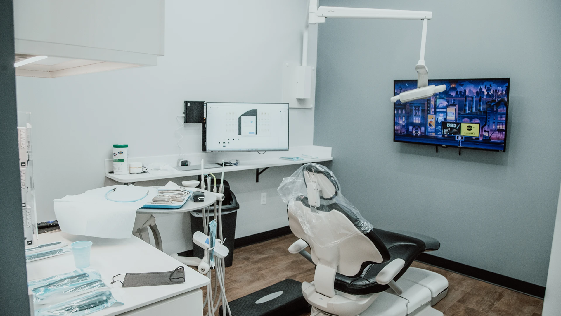 a dental exam room with a chair facing a tv