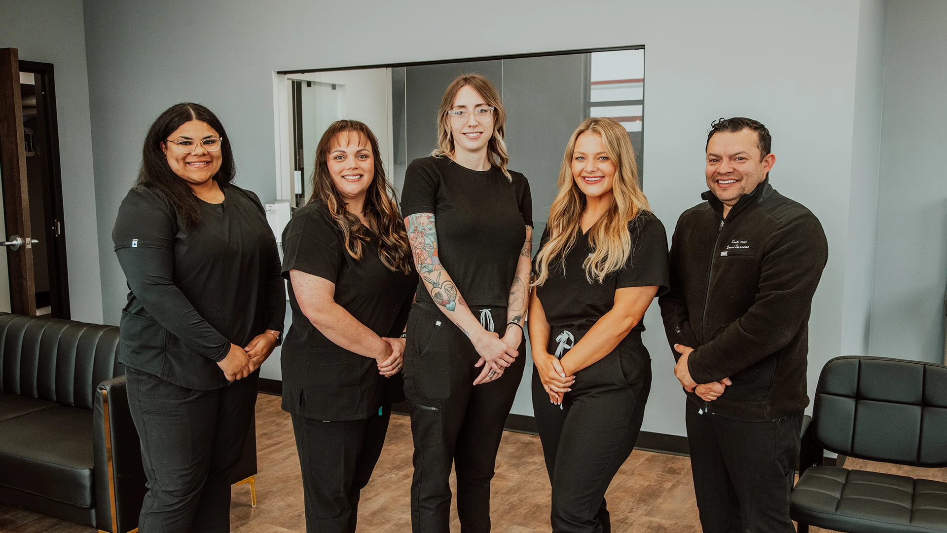 group of people wearing black scrubs posing in dental lobby