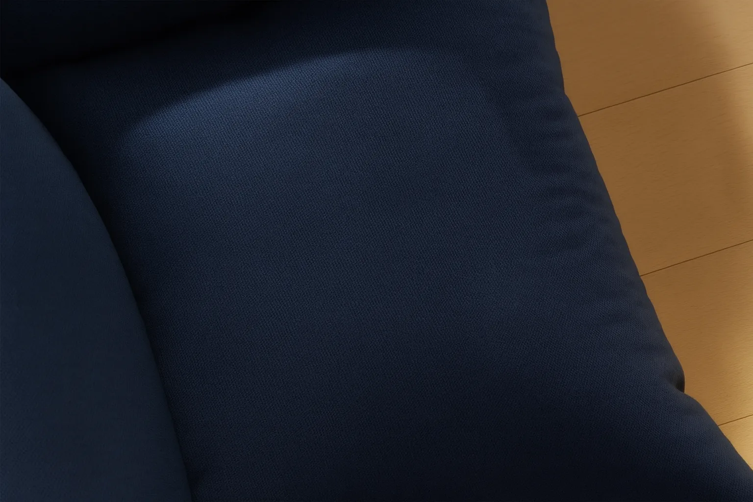 Close-up of a dark blue cushioned fabric surface next to a light wood floor.