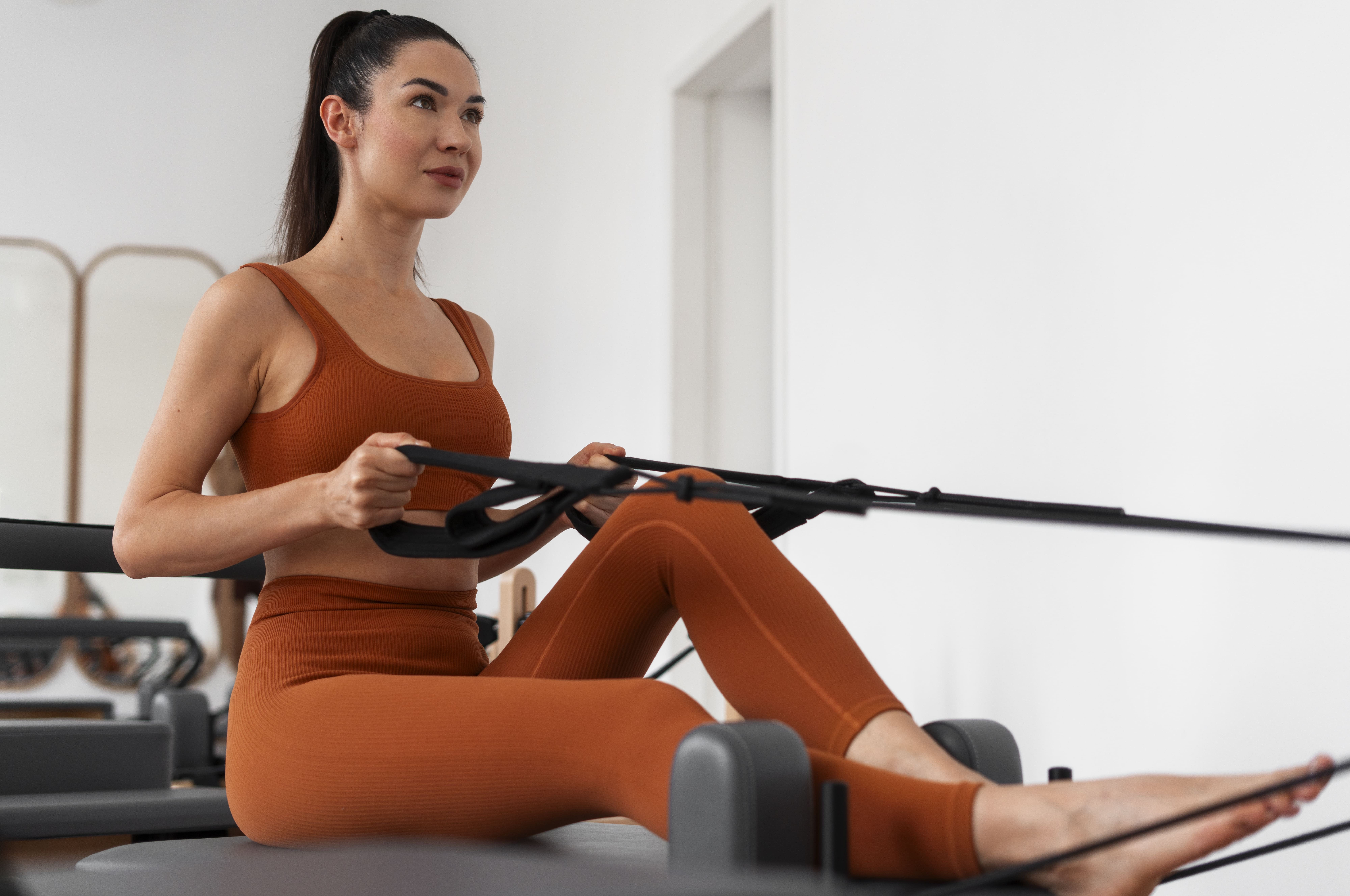 Woman training on a Megaformer, the machine used in the Lagree method, in a bright boutique studio