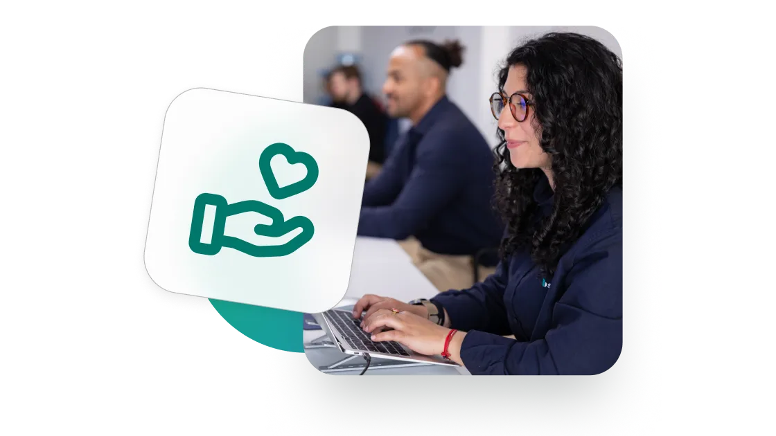 Une femme aux cheveux bouclés et portant des lunettes, en train de taper sur un ordinateur portable, avec un cœur et une main superposés pour symboliser le soutien.