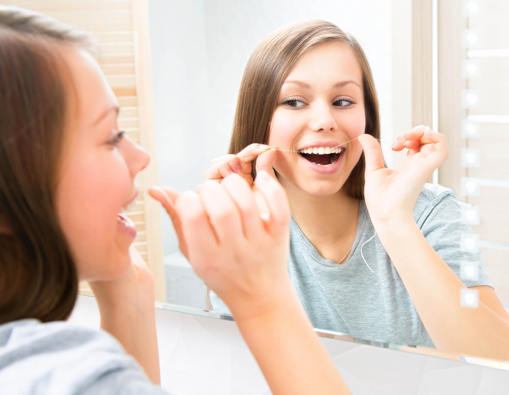 teenage girl flossing as instructed by a Dentist in Hamburg NJ