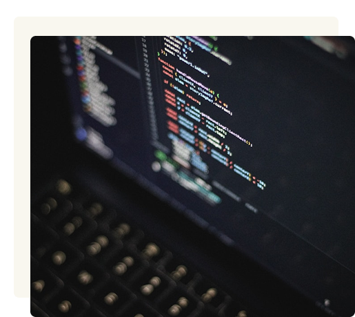 Close-up of a laptop keyboard and screen displaying lines of colorful programming code on a dark background.