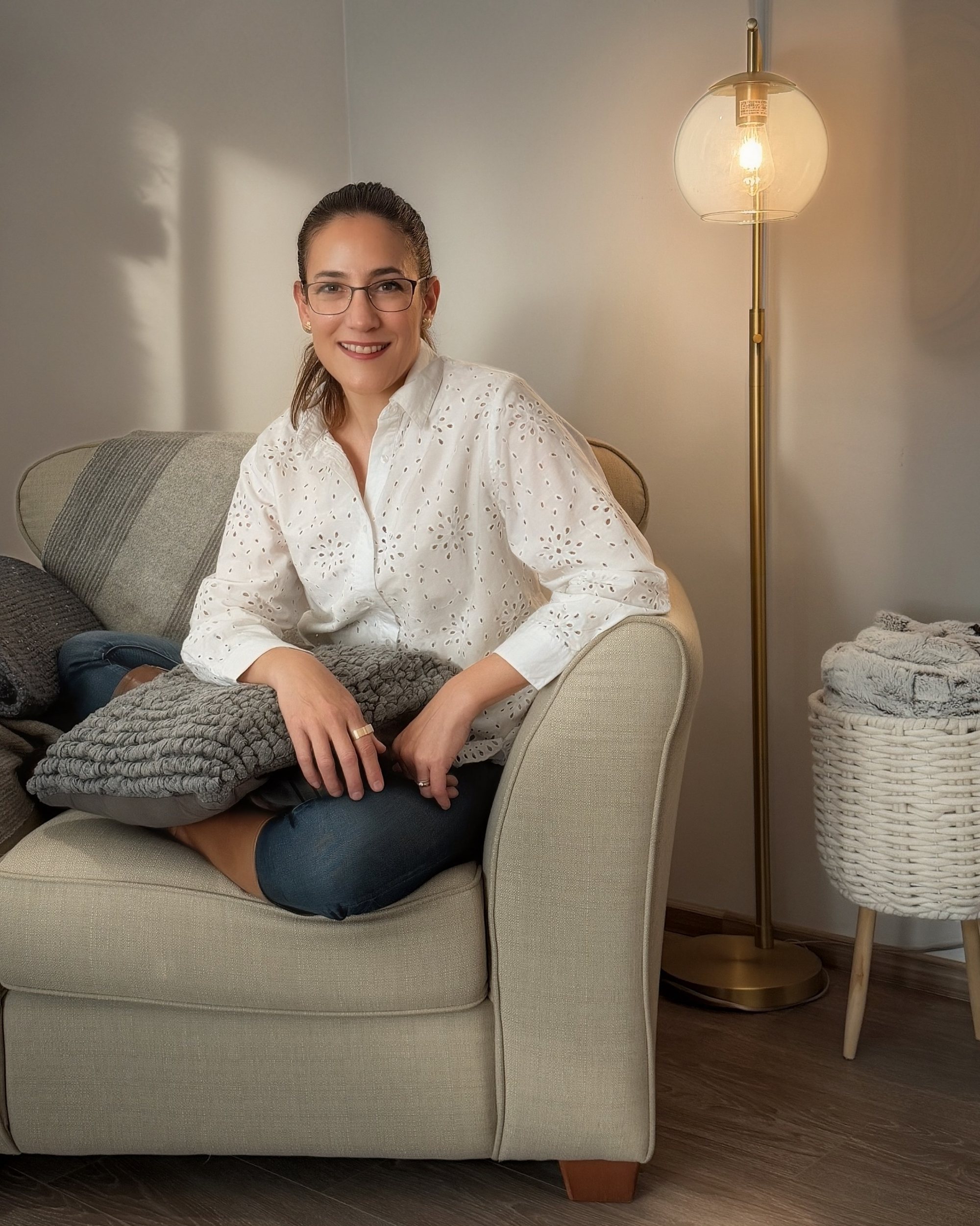 Woman wearing glasses and a pink and purple striped shirt smiling indoors.