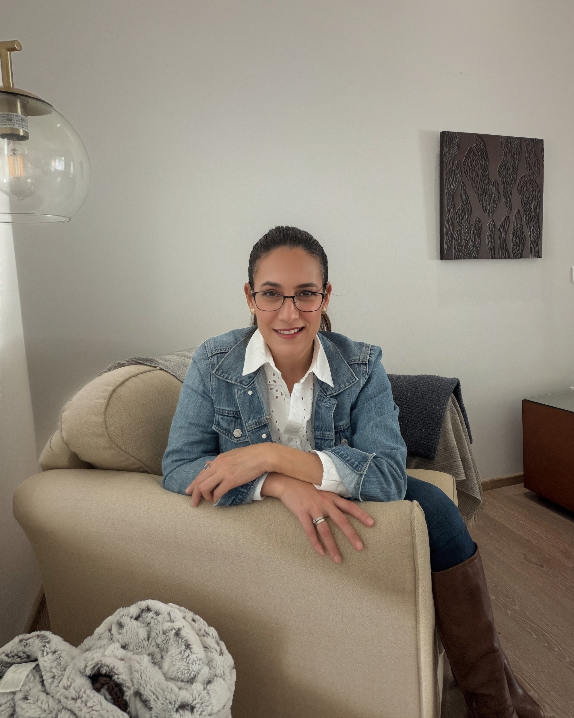 Woman wearing glasses and a pink and purple striped shirt smiling indoors.
