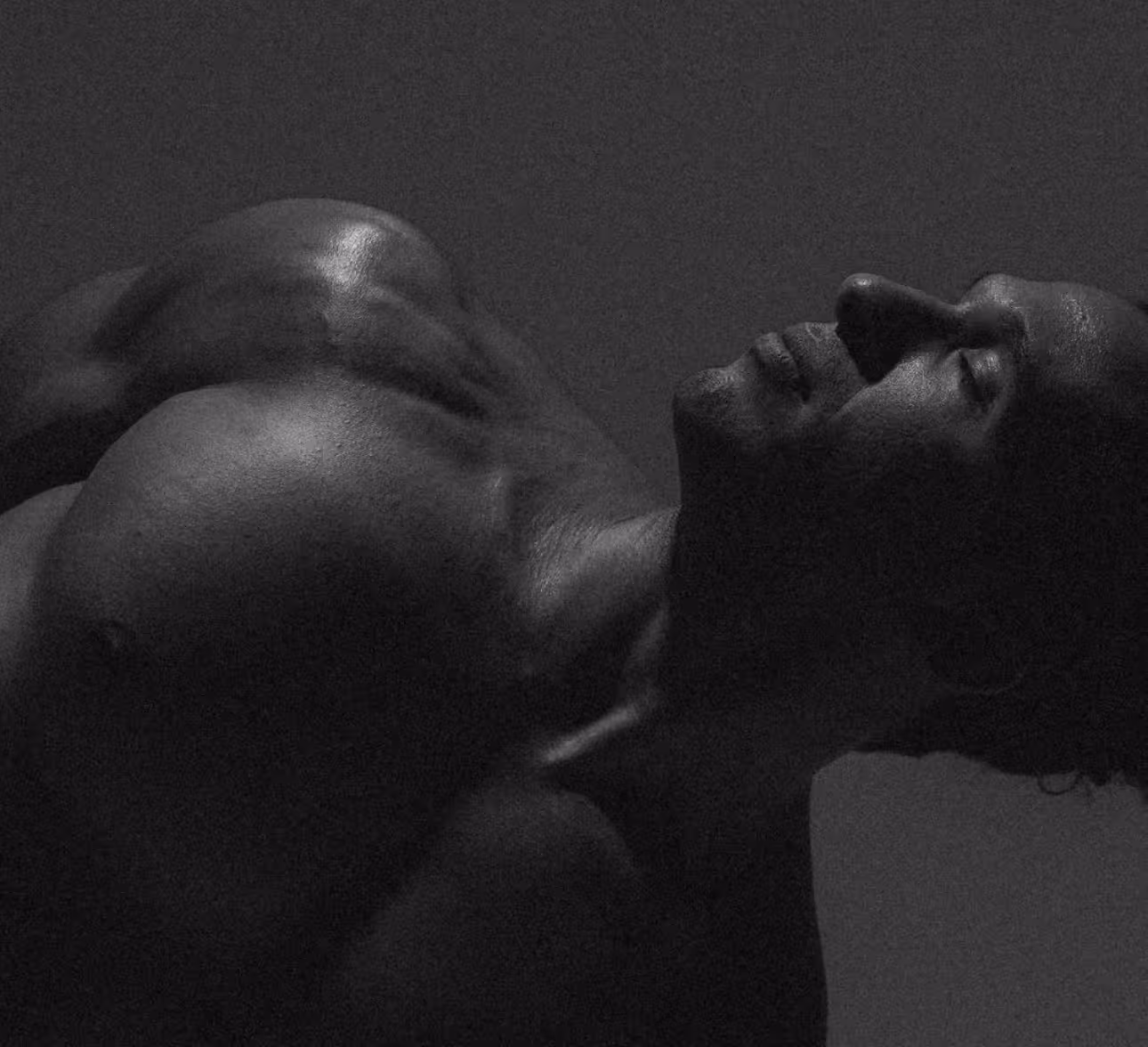 Close-up black and white portrait of Jonah Kest arching backward with eyes closed, highlighting the physical intensity of yoga practice