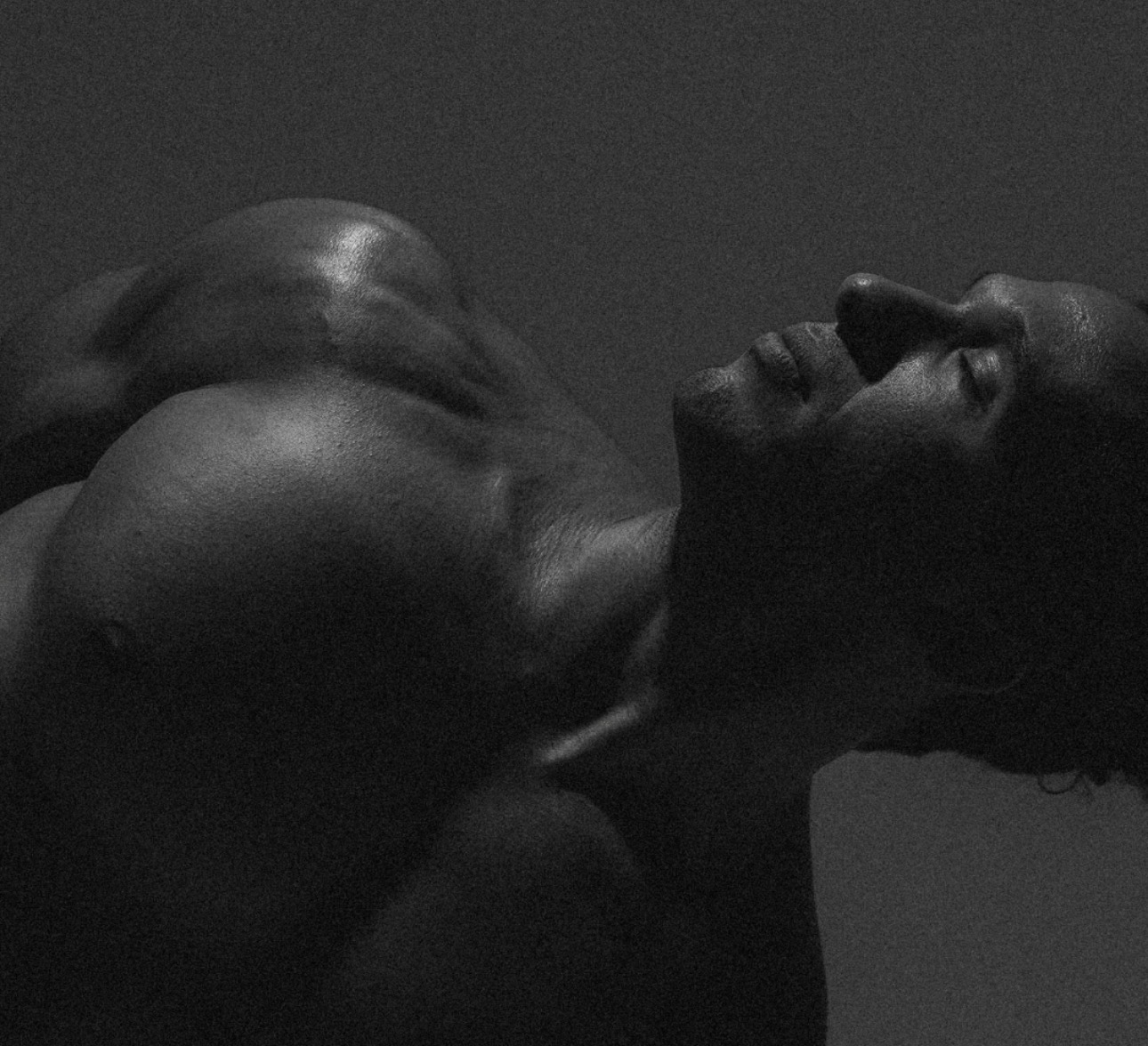 Close-up black and white portrait of Jonah Kest arching backward with eyes closed, highlighting the physical intensity of yoga practice