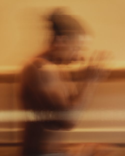 Blurred figure of a person seen through textured glass with warm golden lighting, evoking a sense of inner stillness