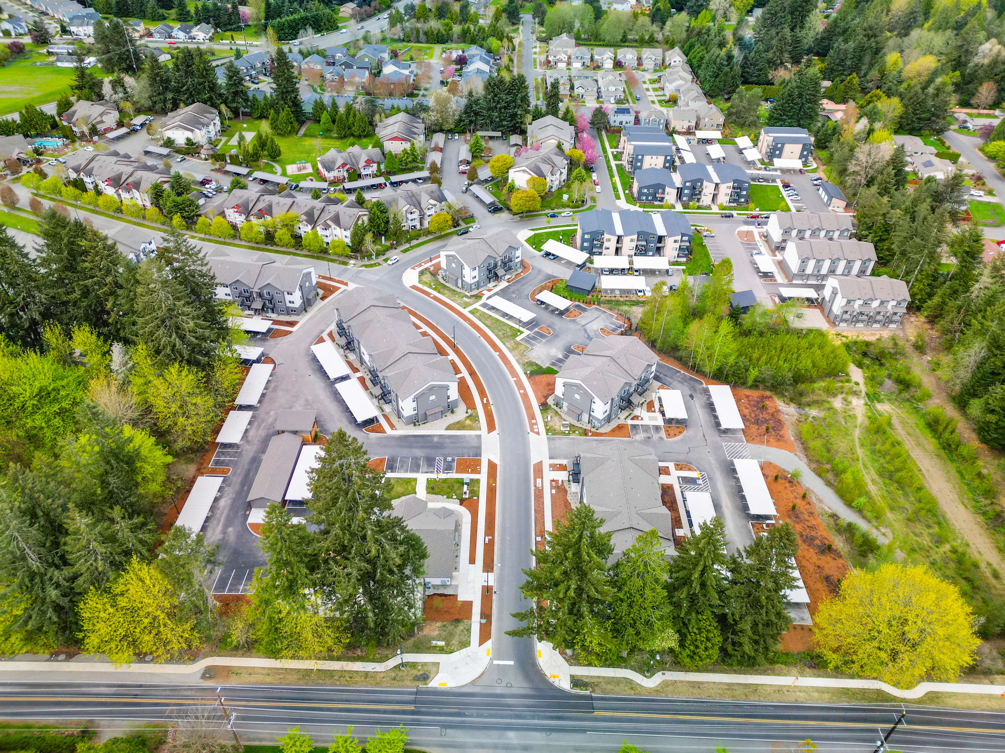 Aerial view of a residential neighborhood with multiple apartment buildings, green trees, and roadways.
