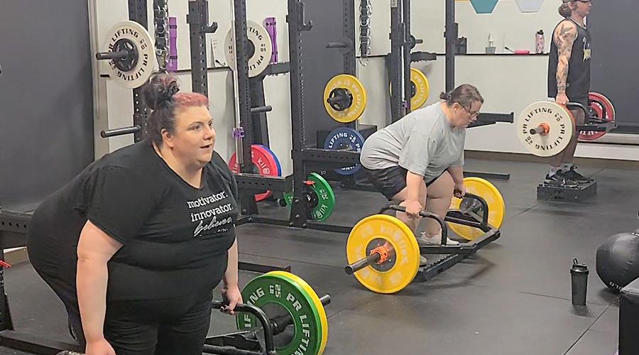 A line up of three powerlifters of varying body types deadlifting in an open gym space.