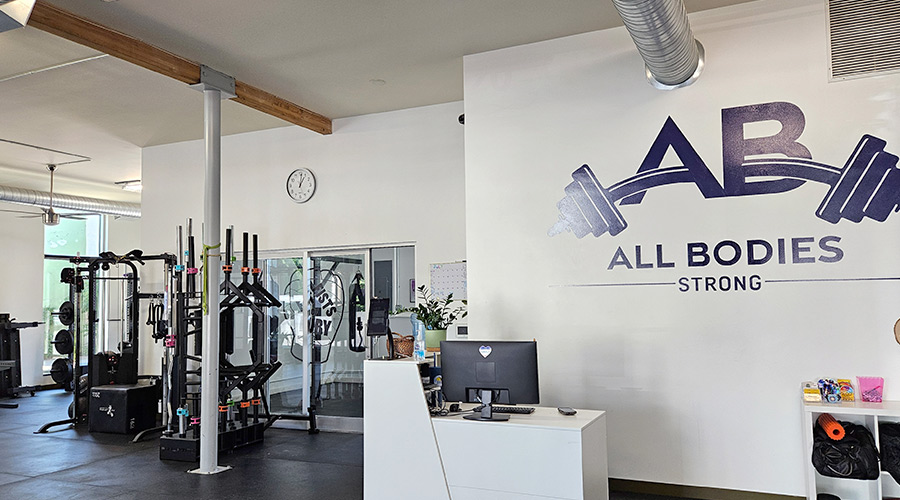 A photo of the All Bodies Strong gym showing bright lighting and open floor space.