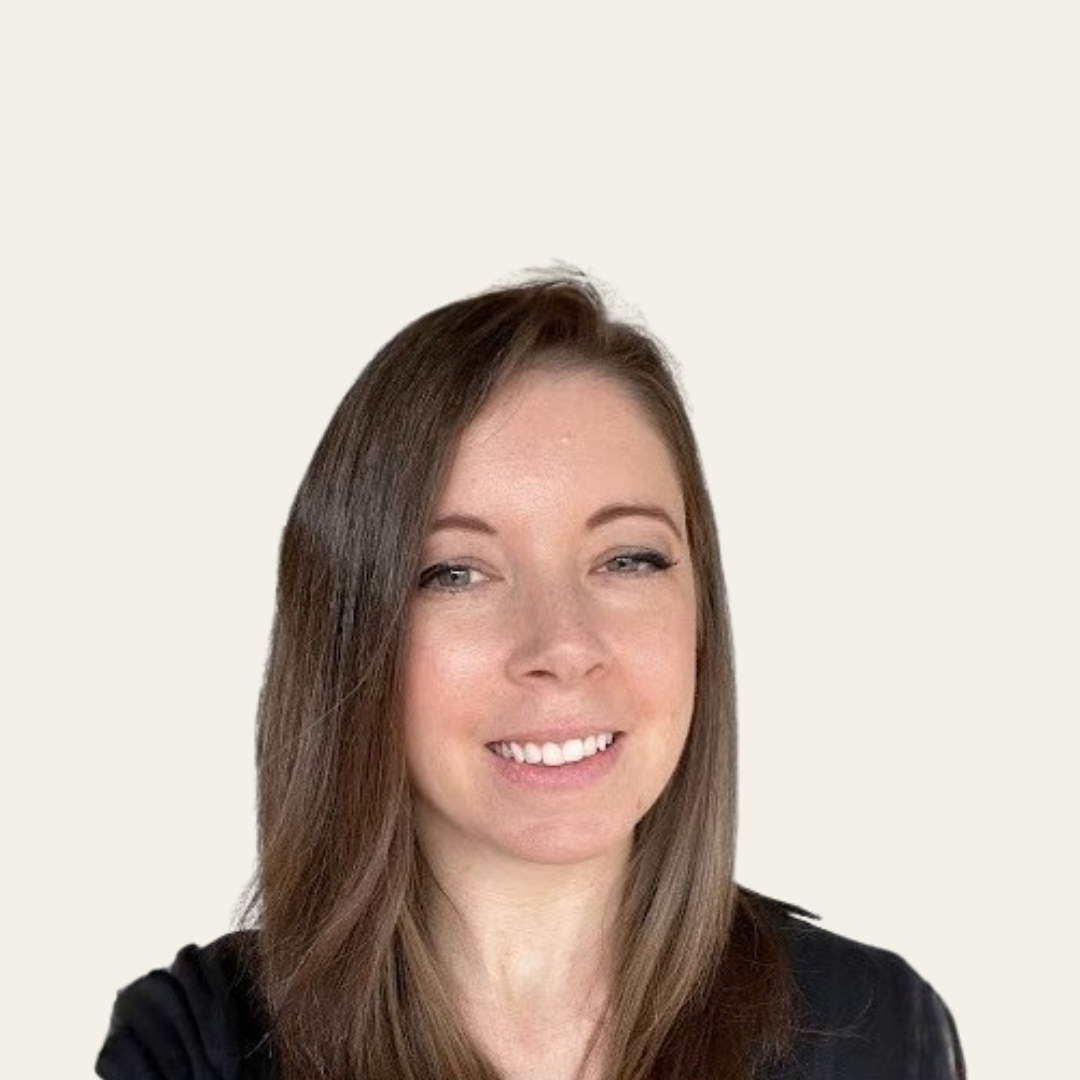 Smiling woman with long brown hair wearing a black top against a plain light background.
