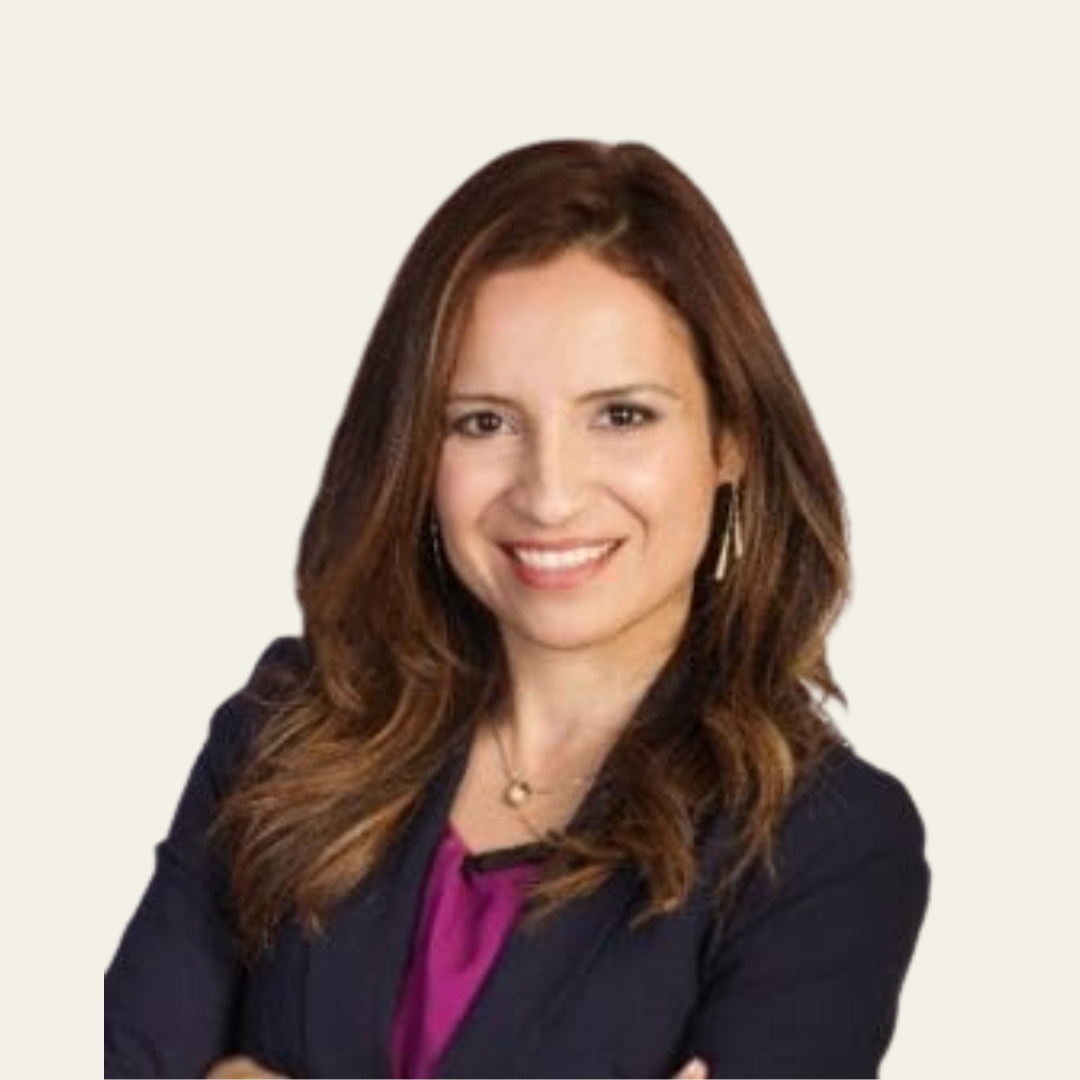 Smiling woman with long brown hair wearing a navy blazer and magenta top against a plain light background.