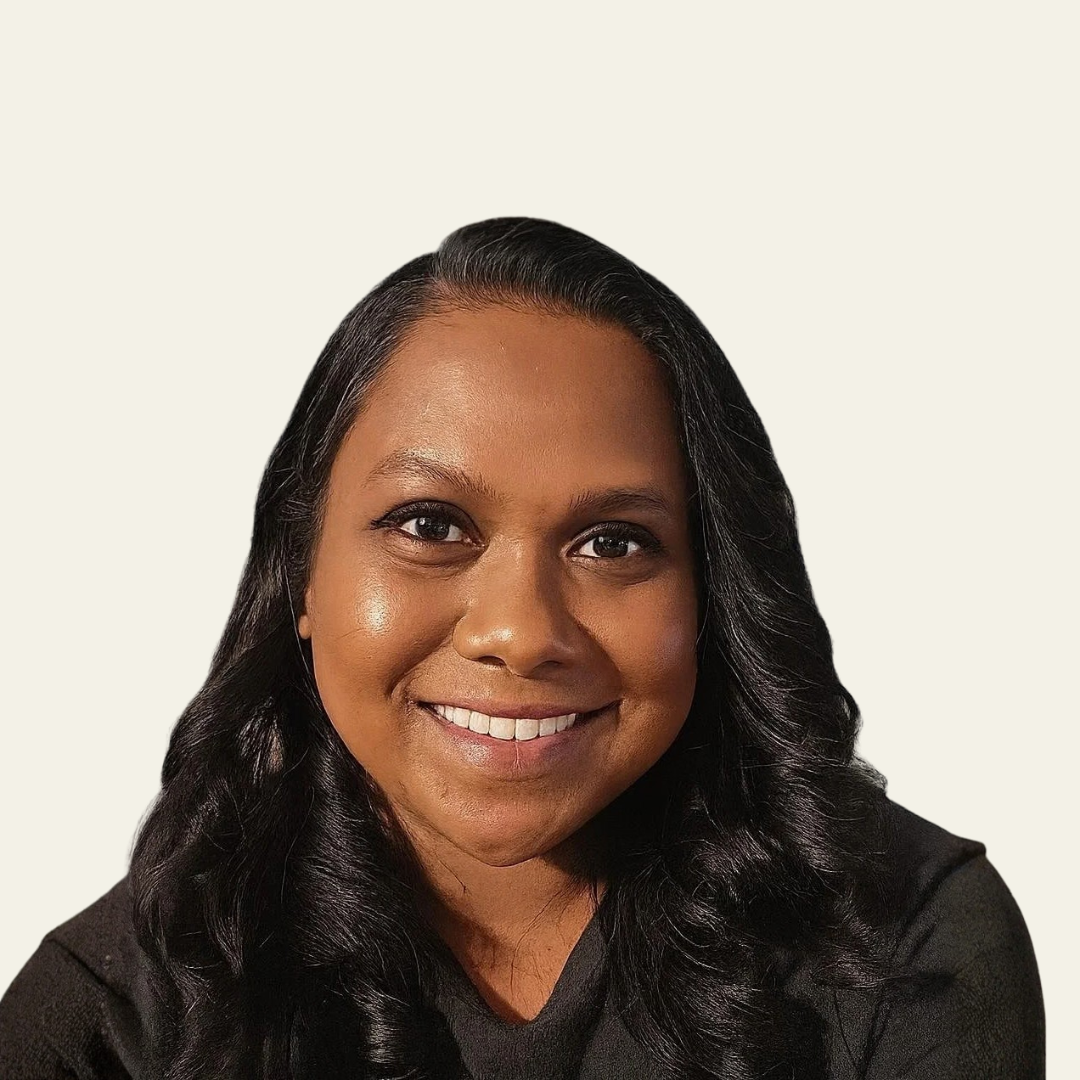 Smiling woman with long, wavy dark hair against a plain light background.