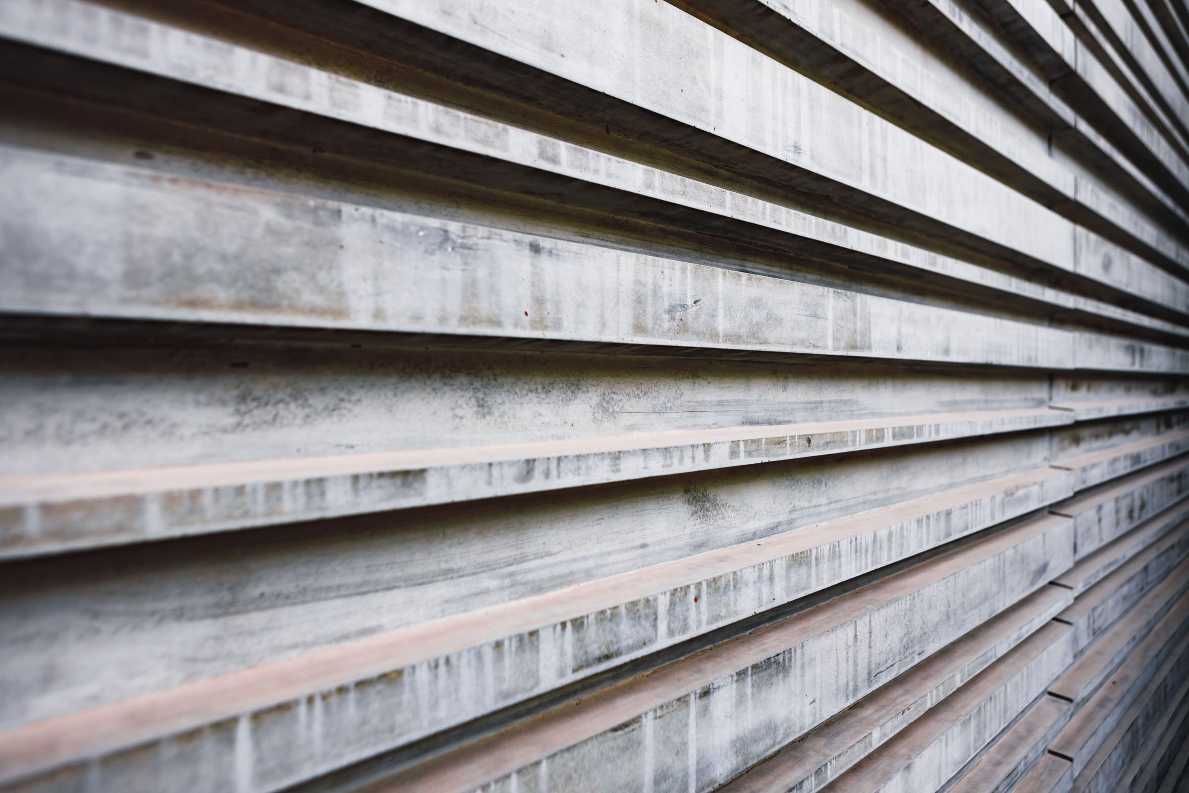 Close-up of a concrete wall with horizontal ridged panels showing weathering and stains.