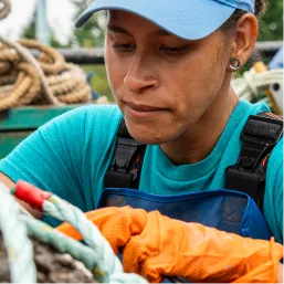Field technician in gloves hauling a rope aboard a work vessel