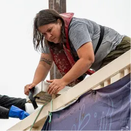 Crew member in a life vest leaning over a barge edge to secure a strap