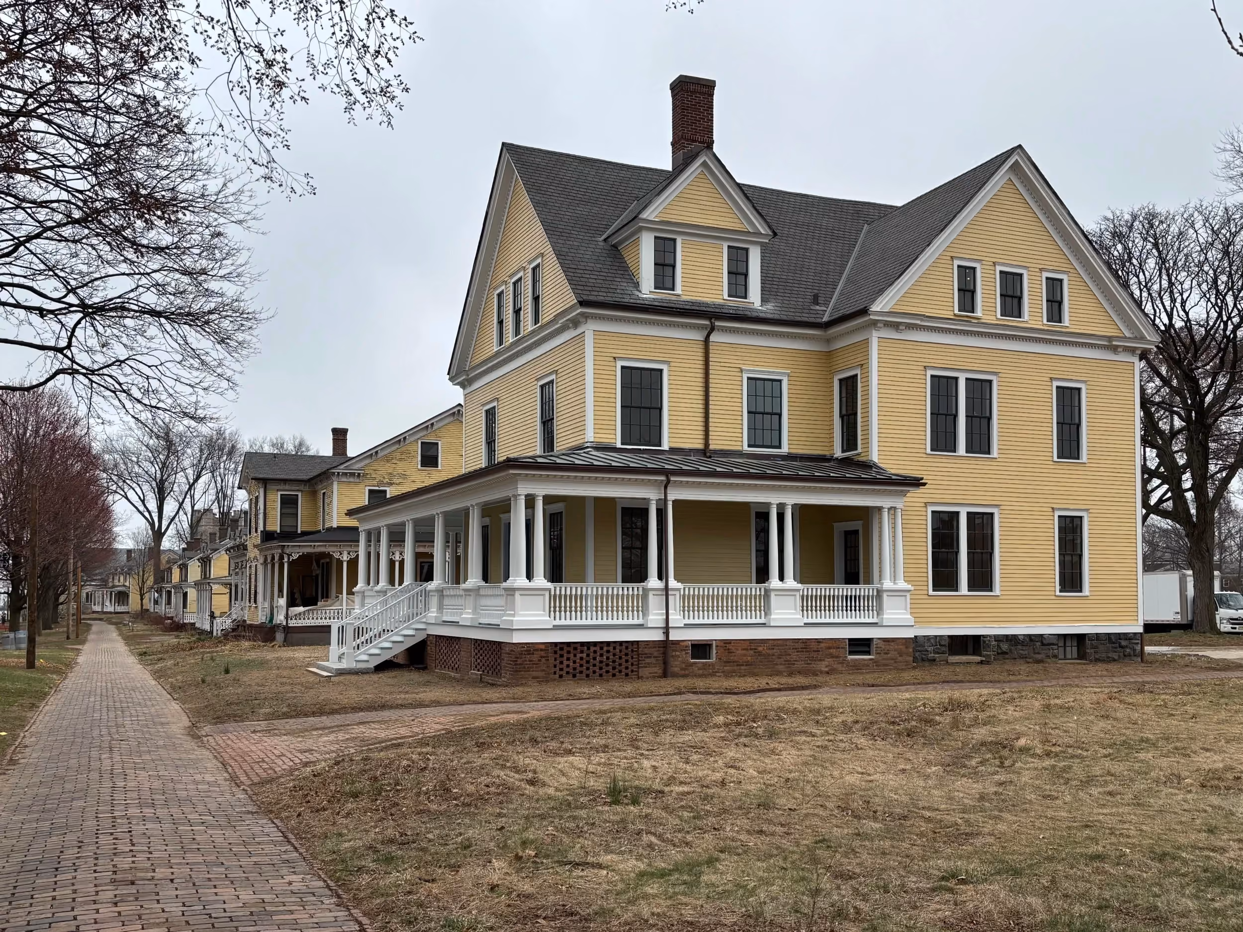 Restored yellow Victorian house with wraparound porch in Nolan Park on Governors Island